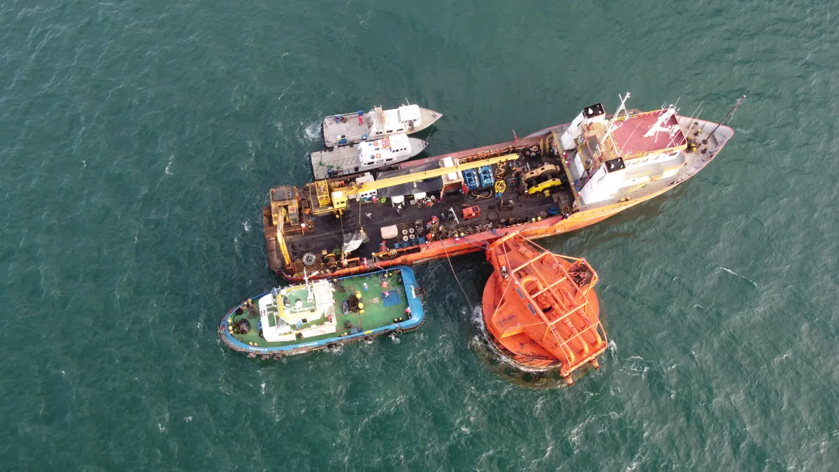 Crane barge and tug carrying out the offshore installation of a mooring buoy.